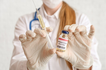 Female doctor with monkeypox vaccine and syringe on white background, closeup