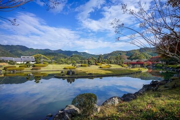 鮮やかな朱色の橋がある日本庭園の秋の情景＠愛媛
