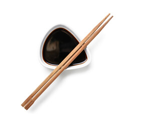 Bowl of soy sauce and chopsticks on white background