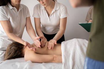 Teacher helping student training to become masseus, health wellness massage training