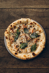 italian pizza with burnt sides on a wooden background top view. pizza with white truffles, mushrooms, basil leaves. sliced pizza close-up