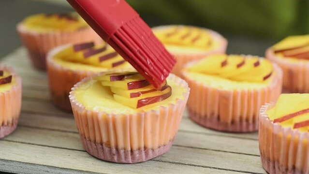 Chef using culinary brush to apply honey on mini nectarine cheesecakes.
 - Powered by Adobe