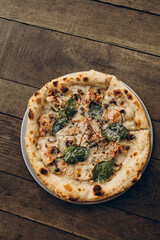 italian pizza with burnt sides on a wooden background top view. pizza with white truffles, mushrooms, basil leaves. sliced pizza close-up	
