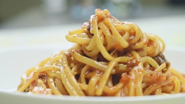 The cook serves pasta alla norma.
