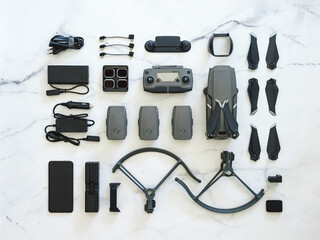 Set of folding drone or quadcopter with many accessories, top view or flat lay. Kit of folding drone and equipment for UAV over white marble background. Creative layout