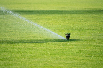 Sprinkler system working on fresh green grass on football (soccer) stadium