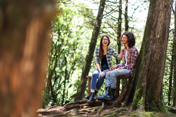 Naklejka na ściany i meble Young latin couple sitting in the forest smiling and woman with expression at Costa Rica