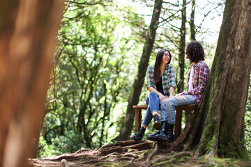 Naklejka na ściany i meble Young latin couple sitting in the forest smiling looking each other at Costa Rica