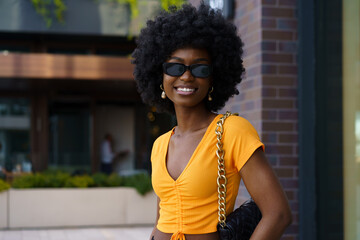 Fototapeta na wymiar Portrait of young black woman with afro hairstyle smiling in urban background