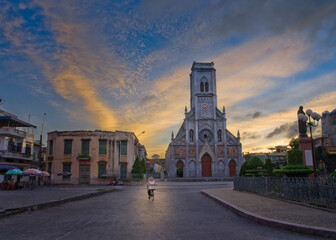 Obraz premium A woman riding a bicycle in front of an ancient church in early morning.