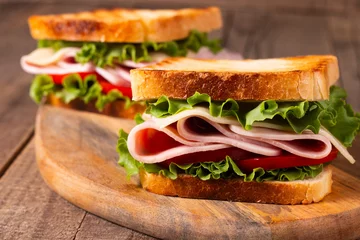  Close-up of two toasted sandwiches with fresh ham, cheese and vegetables on background. Club sandwich and take-away concept. Fast food.  © xander21
