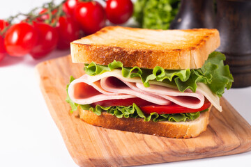 Close-up of two toasted sandwiches with fresh ham, cheese and vegetables on background. Club sandwich and take-away concept. Fast food. 