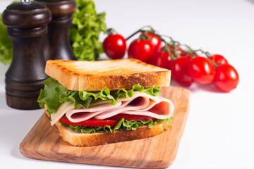 Close-up of two toasted sandwiches with fresh ham, cheese and vegetables on background. Club sandwich and take-away concept. Fast food. 