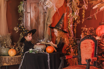 Little boy and girl in a black witch costumes and hats in a Halloween decorations.Halloween concept.Selective focus.