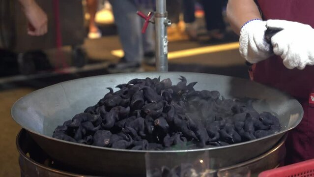 Cinematic zoom shot capturing hand cracking open unique food choice, water caltrop, bat nut, selling at tourist attraction famous street food night market in Taiwan.