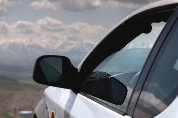 Fototapeta na wymiar SUV concept with mountains in the clouds. Close-up of the nose of the car