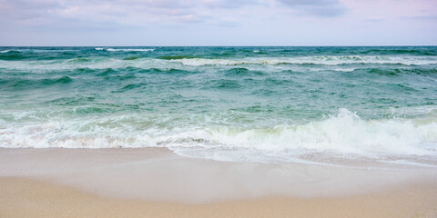 stormy weather in velvet season. seascape with clouds in evening light. waves crashing sandy beach. windy weather