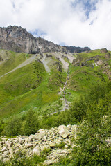Obraz premium Beautiful landscape - green hills in the terskol valley with bright grass and high gray rocks with sharp peaks and stones on a clear summer sunny day near elbrus russia