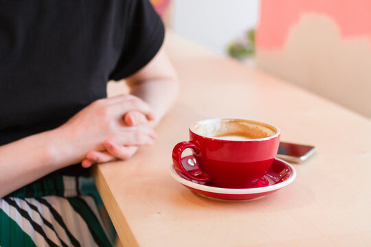 Cup of coffee on a table with mobile phone on a background of hands of woman. 