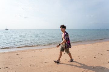 Portrait of young asian man walking by at the beach on summer vacation