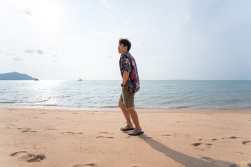 Portrait of young asian man walking by at the beach on summer vacation