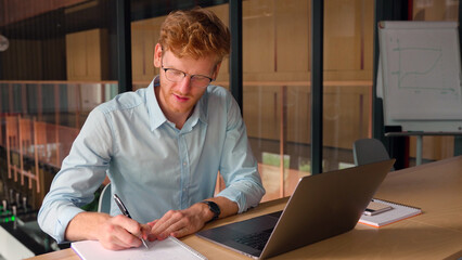 Portrait of successful confident young businessman make notes in office.