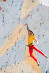 Plakat Sportsman climber hanging with one hand on an artificial climbing wall outdoors.
