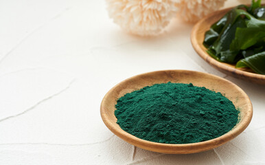 laminaria or kelp seaweed and spirulina powder in wood plate background. spirulina powder with konbu and alga food on white table background.                                                           