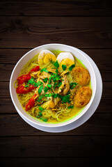 INDONESIAN CULINARY CHICKEN SOUP NOODLE WITH SLICE BOILING EGG AND FRIED MASHED POTATOS AS TOPPING
