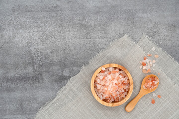 Himalayan pink salt in a wooden cup on cloth.