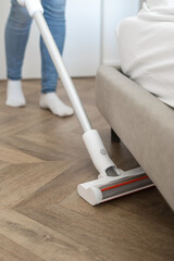 Housewife with handheld appliance vacuuming parquet floor