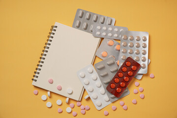 Medicine pill or drug for illnesses with notebook on yellow background, viruses, epidemics. online purchase of medicines.  copy space. Pharmacy concept.