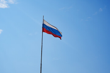 the Russian flag flies against the blue sky. 