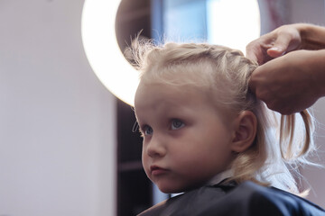 Barber woman make fashionable pretty hairstyle for cute little girl