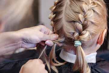 Barber woman make fashionable pretty hairstyle for cute little girl