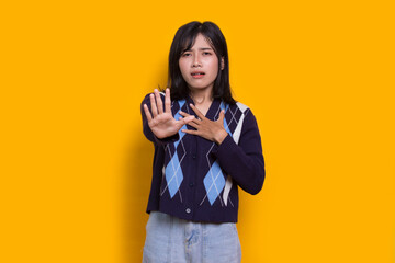 young woman with open hand doing stop sign with serious expression defense gesture isolated on yellow background
