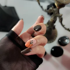  Witch woman hands with black nail polish and orange pumpkin design, halloween and all saints manicure © Vera Bel