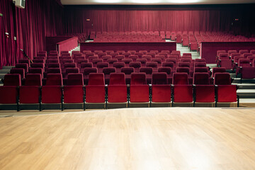 Empty red chairs and stage for audience in the theater