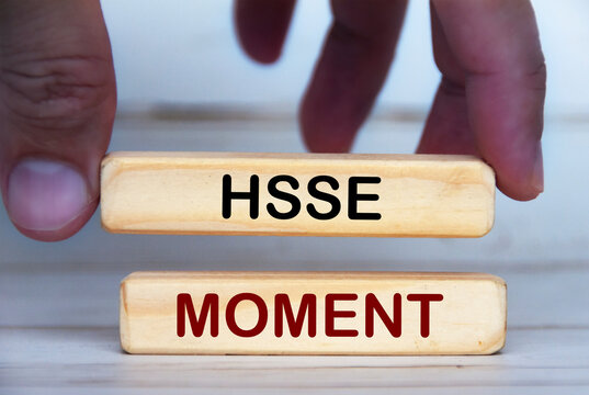 Hand holding wooden blocks with text - HSSE Moment. Conceptual