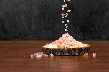 Himalayan pink salt and a wooden tray on wooden background