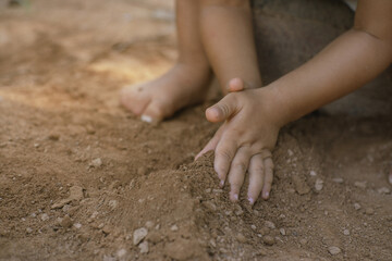 Fototapeta na wymiar Hand of boy playing dirt soil on ground.
