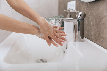 Washing hands under the flowing water tap. Hygiene concept hand detail. Washing hands rubbing with soap for corona virus prevention, hygiene to stop spreading corona virus in or public wash room.