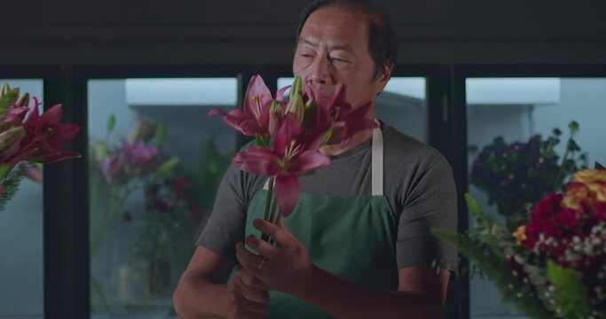 A small business employee of flower shop creating a bouquet of flowers arraignment. An Asian American entrepreneur creating artisan bouquet for client