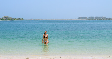 European woman in bikini walking in the water, Jumeirah beach, Dubai