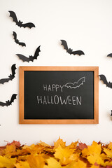 A sign saying 'Happy Halloween' surrounded by black bat and orange leaves