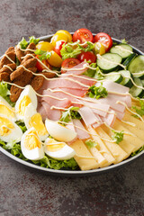 Beautiful and delectable Chef Salad with eggs. ham, cheese, fresh tomatoes, cucumbers and seasoned croutons closeup in the plate on the table. Vertical