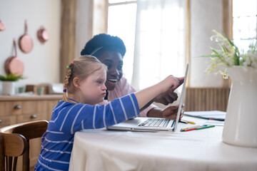 A girl with down syndrome having a lesson with her teacher and looking involved