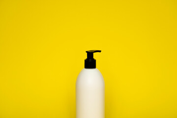 White plastic soap dispenser pump bottle isolated on yellow background. Skin care lotion. Bathing essential product. Shampoo bottle. Bath and body lotion. Fine liquid hand wash. Bathroom accessories.