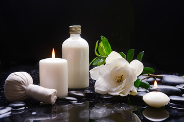 Still life of with 
gardenia, and spa ball , zen black stones with oil bottle on wet background
