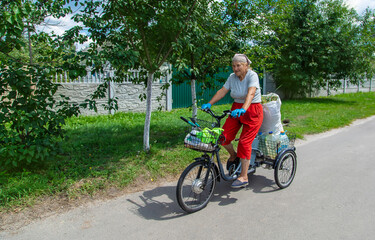 An old woman rides a bicycle. Selection focus.